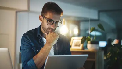 Personne en chemise jean utilisant une tablette dans un bureau moderne avec des plantes et un éclairage chaud.