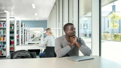 un homme est assis à une table dans une bibliothèque